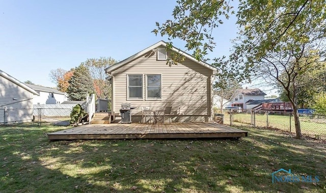 rear view of property featuring a lawn, fence, and a wooden deck