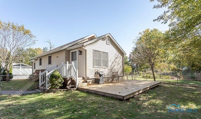 rear view of house with a deck, a yard, and fence