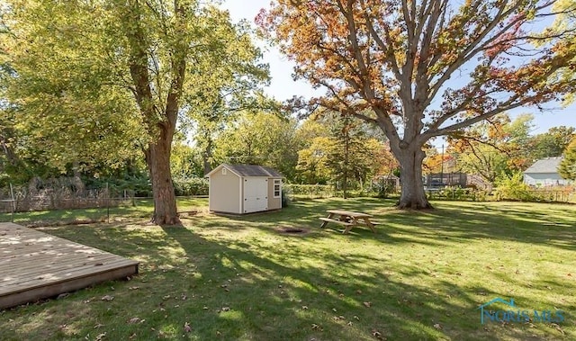 view of yard with a deck, an outbuilding, fence, and a shed