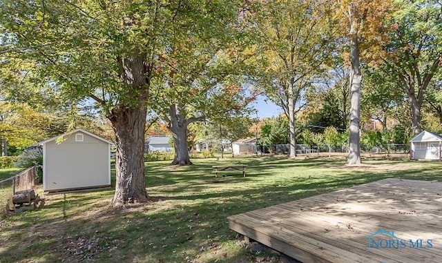 view of yard featuring a deck, an outbuilding, a fenced backyard, and a shed