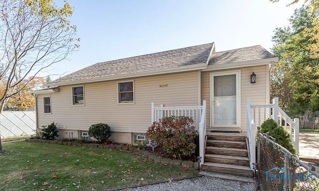 view of front facade with roof with shingles, a front lawn, and fence