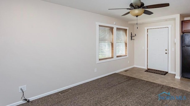 carpeted foyer entrance featuring visible vents, baseboards, and a ceiling fan