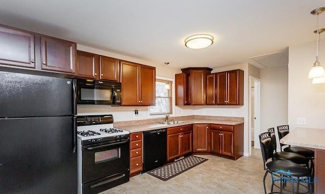 kitchen featuring a sink, black appliances, pendant lighting, and light countertops