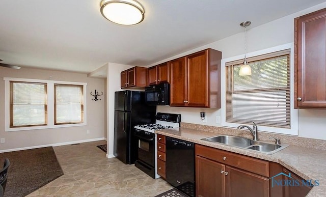 kitchen with baseboards, a sink, hanging light fixtures, black appliances, and light countertops