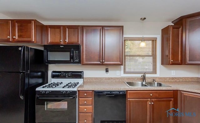 kitchen featuring hanging light fixtures, black appliances, light countertops, and a sink