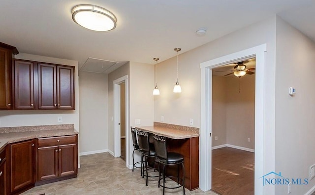 kitchen featuring hanging light fixtures, light countertops, a ceiling fan, and baseboards