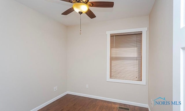 empty room with dark wood finished floors, visible vents, a ceiling fan, and baseboards