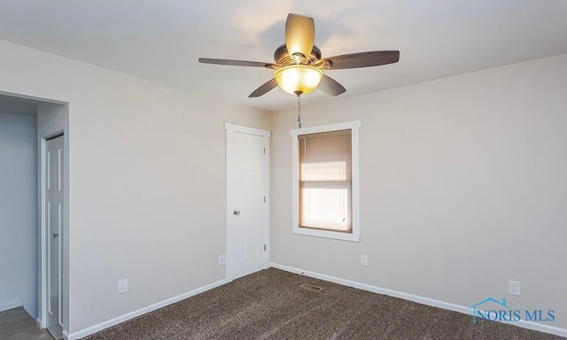 empty room featuring ceiling fan, baseboards, and dark colored carpet