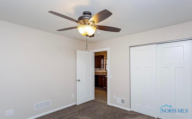 unfurnished bedroom with a closet, baseboards, visible vents, and dark carpet