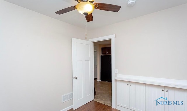 spare room featuring visible vents, baseboards, ceiling fan, and dark wood-style flooring