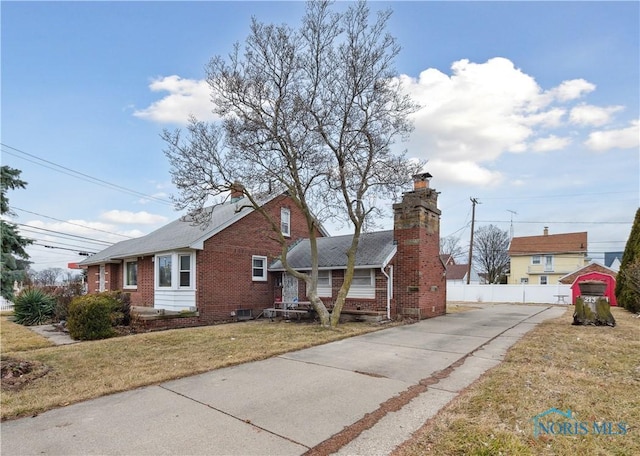 view of front of house featuring a front yard, fence, brick siding, and a chimney