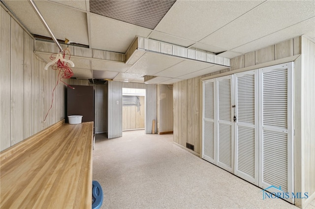 finished below grade area featuring carpet flooring, wood walls, and a paneled ceiling