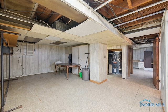 unfinished basement with tile patterned floors, baseboards, and wooden walls