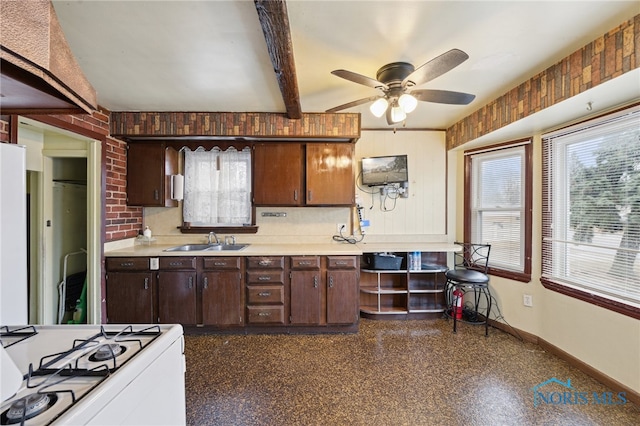 kitchen with a sink, baseboards, plenty of natural light, and white gas range