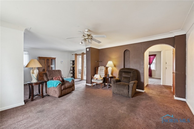 living room featuring carpet, baseboards, arched walkways, and ornamental molding