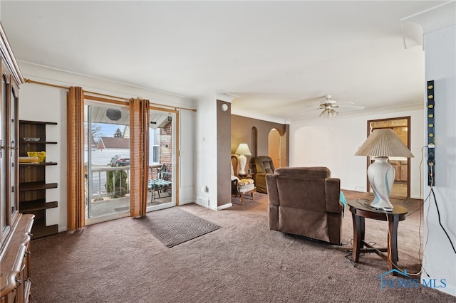 carpeted living room with arched walkways, crown molding, and a ceiling fan