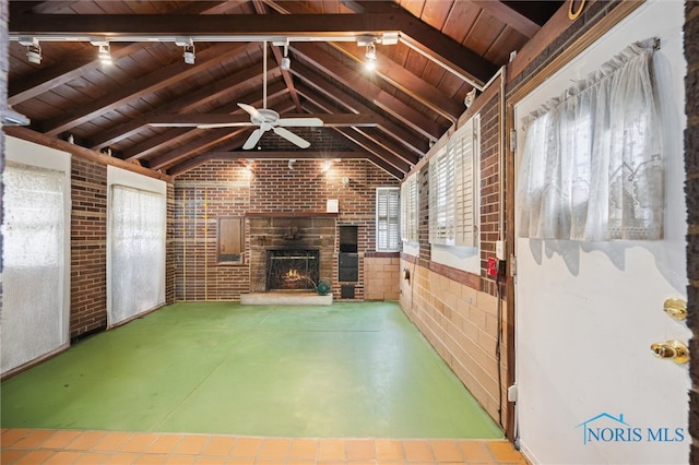 unfurnished living room featuring wood ceiling, a warm lit fireplace, brick wall, and vaulted ceiling with beams