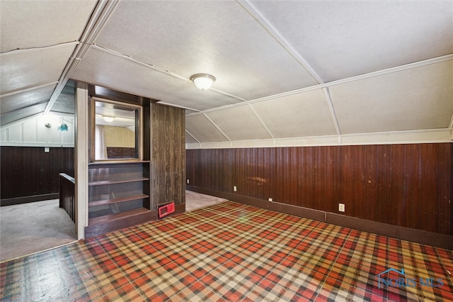 additional living space featuring wooden walls, carpet, and vaulted ceiling