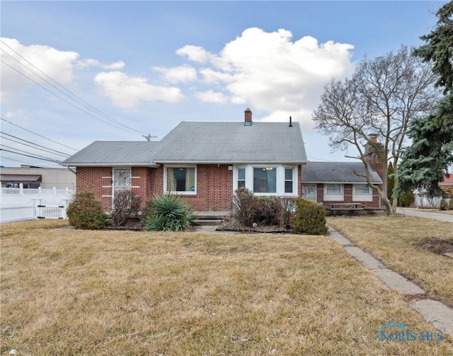 view of front of property featuring a front yard, fence, and brick siding