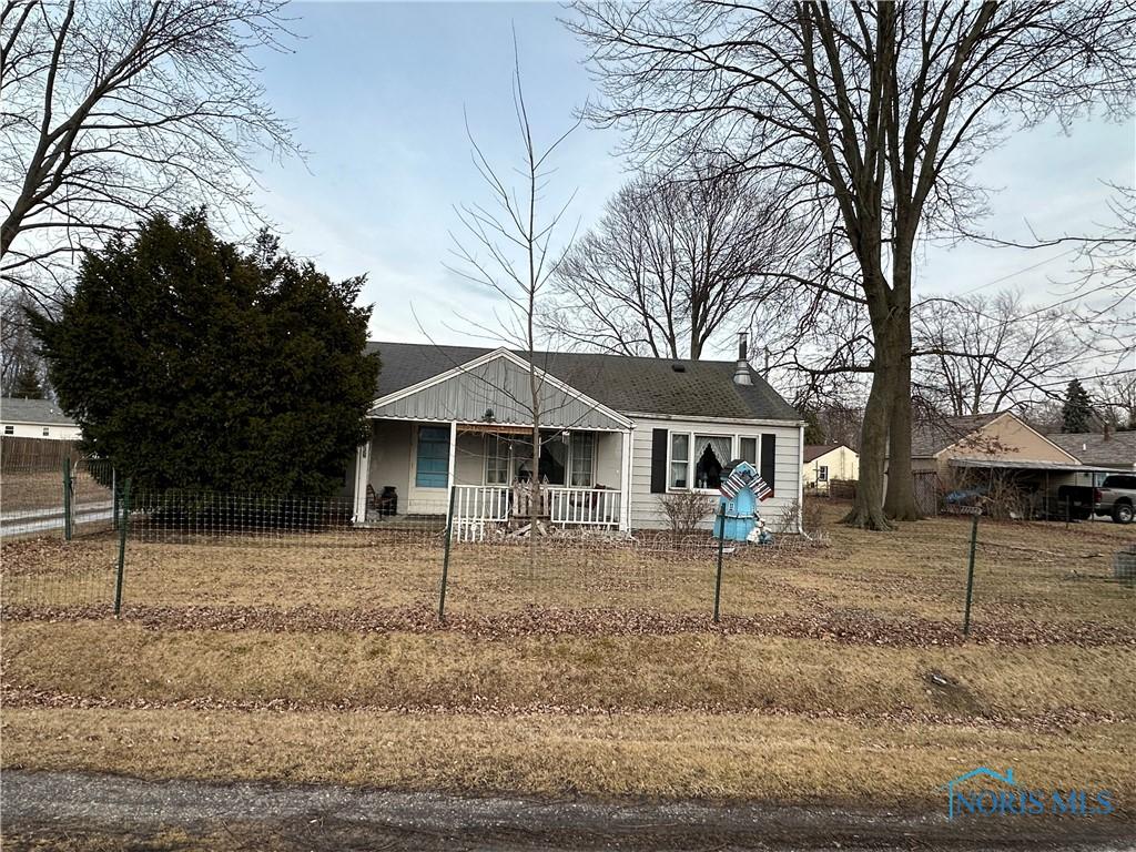 view of front facade featuring a porch, a fenced front yard, and roof with shingles