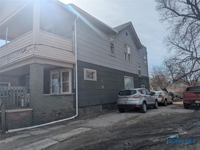 view of side of home featuring a balcony and brick siding