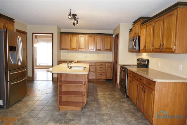 kitchen with a sink, a center island with sink, light countertops, appliances with stainless steel finishes, and open shelves