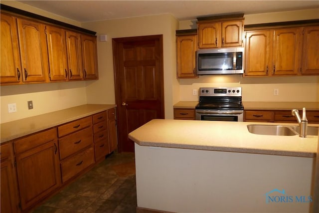 kitchen with a sink, light countertops, brown cabinetry, and stainless steel appliances