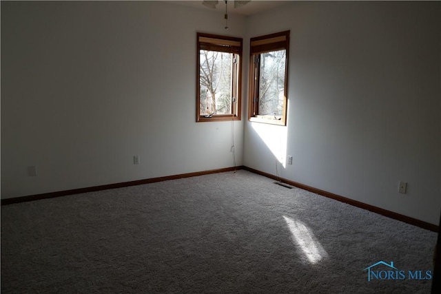 carpeted spare room featuring visible vents and baseboards