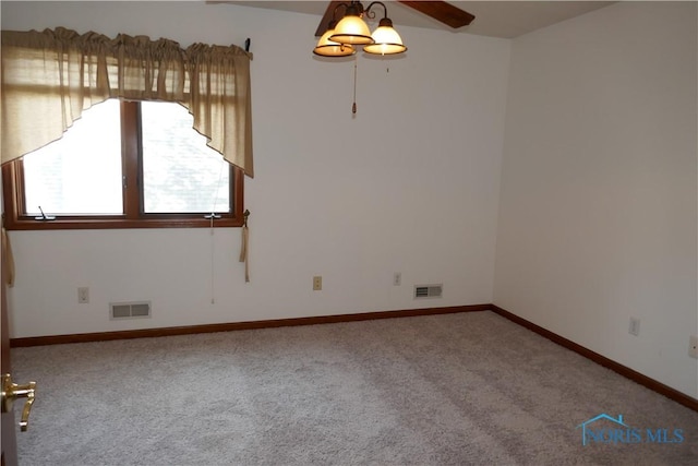 carpeted spare room with visible vents, baseboards, and a ceiling fan