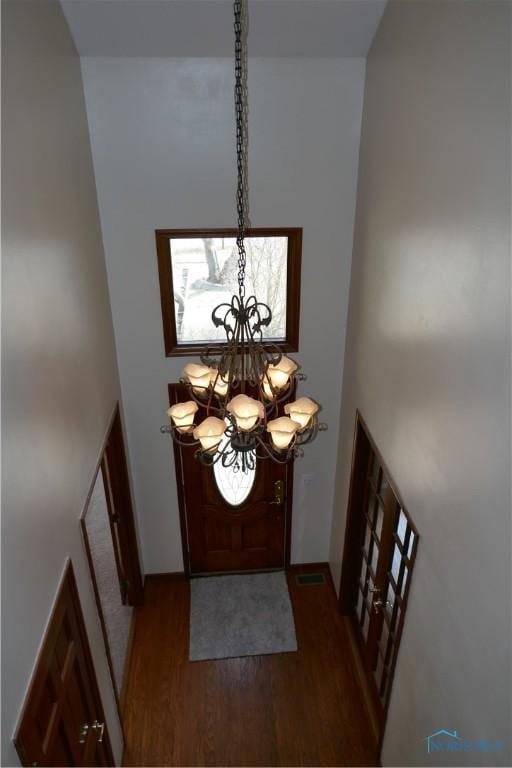 foyer featuring visible vents, baseboards, a chandelier, a high ceiling, and wood finished floors