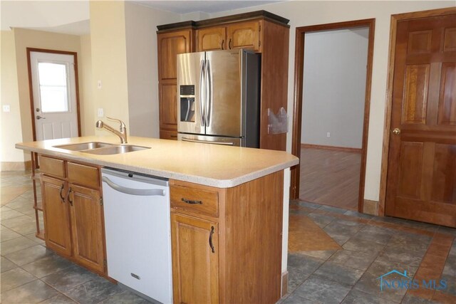 kitchen featuring stainless steel fridge with ice dispenser, a kitchen island with sink, a sink, light countertops, and dishwasher