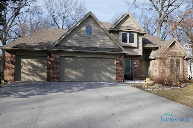 view of front of property with aphalt driveway, an attached garage, brick siding, and roof with shingles