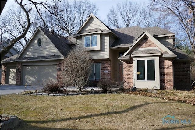 view of front facade with brick siding, a front lawn, roof with shingles, a garage, and driveway