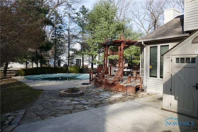 view of patio / terrace with an outbuilding, a fenced in pool, a wooden deck, and a storage shed