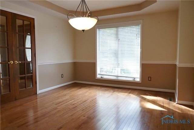 empty room with hardwood / wood-style flooring, french doors, and baseboards