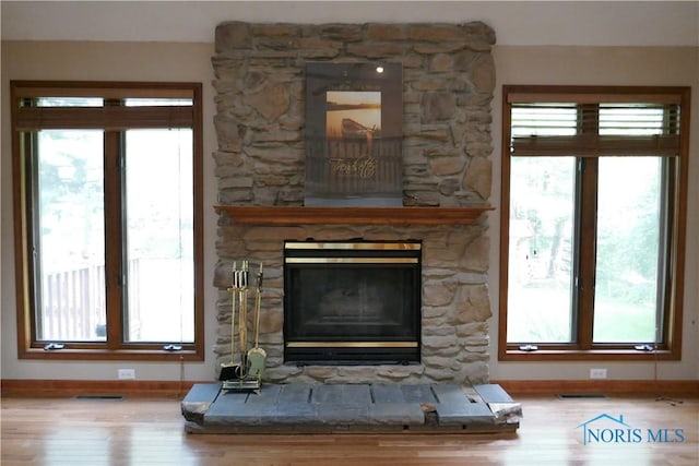 details featuring visible vents, a fireplace, baseboards, and wood finished floors