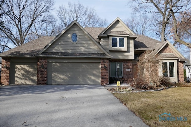 view of front of home with a front yard, an attached garage, a shingled roof, aphalt driveway, and brick siding