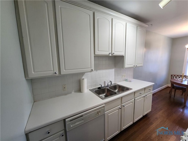 kitchen with dishwashing machine, dark wood finished floors, a sink, white cabinetry, and backsplash