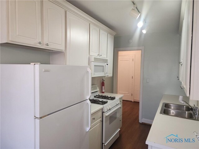 kitchen with dark wood-type flooring, light countertops, white appliances, white cabinetry, and a sink