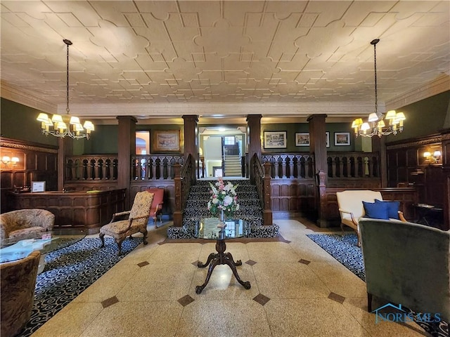 living area with tile patterned floors, a notable chandelier, stairway, crown molding, and decorative columns