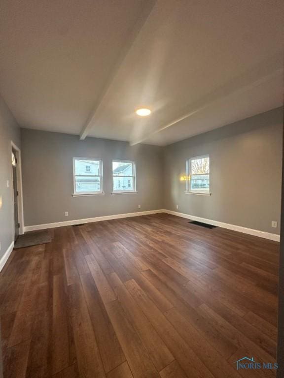 spare room with dark wood finished floors, beamed ceiling, visible vents, and baseboards