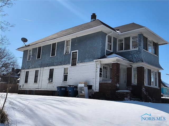 view of snowy exterior featuring a chimney