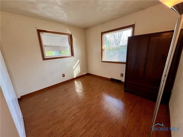 unfurnished bedroom featuring dark wood-type flooring, visible vents, and baseboards