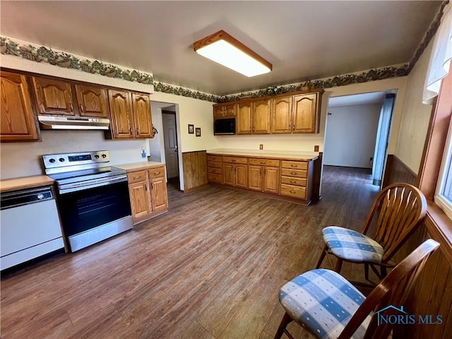 kitchen featuring under cabinet range hood, stainless steel range with electric cooktop, light countertops, and white dishwasher