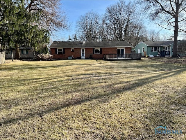 back of property with brick siding, central AC unit, a wooden deck, and a yard