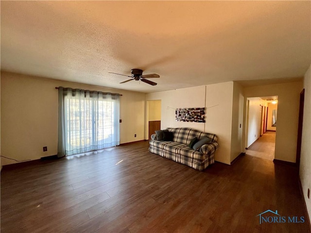 living area with dark wood finished floors, ceiling fan, baseboards, and a textured ceiling