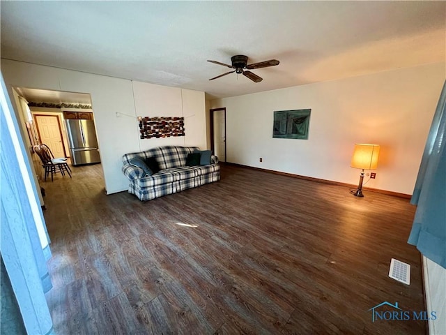 living area featuring visible vents, baseboards, a ceiling fan, and dark wood-style flooring