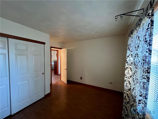 unfurnished bedroom with a closet and dark wood-style flooring