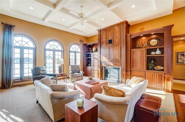 living room with a wealth of natural light, beamed ceiling, coffered ceiling, and visible vents