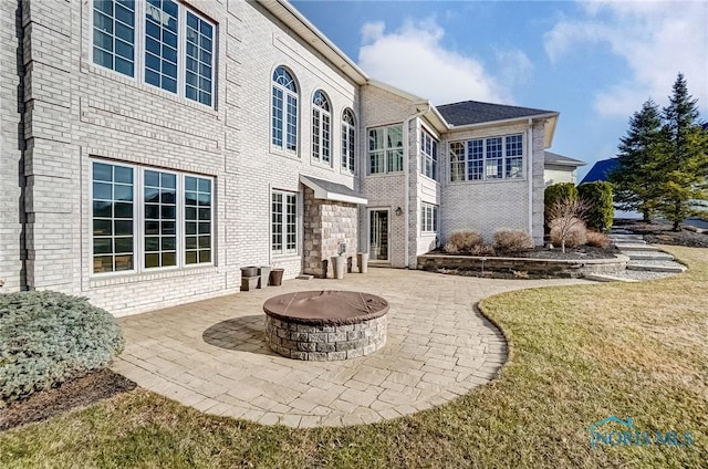 back of house featuring a patio area, brick siding, and a fire pit